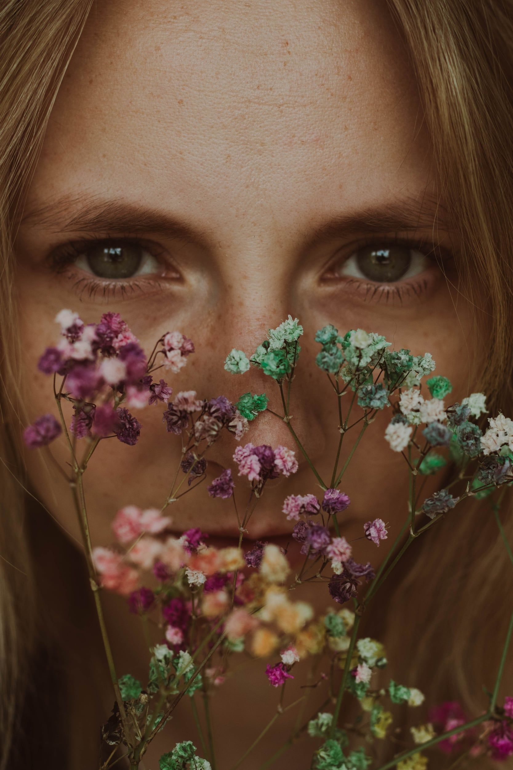 Close portrait with dried flowers held across the face