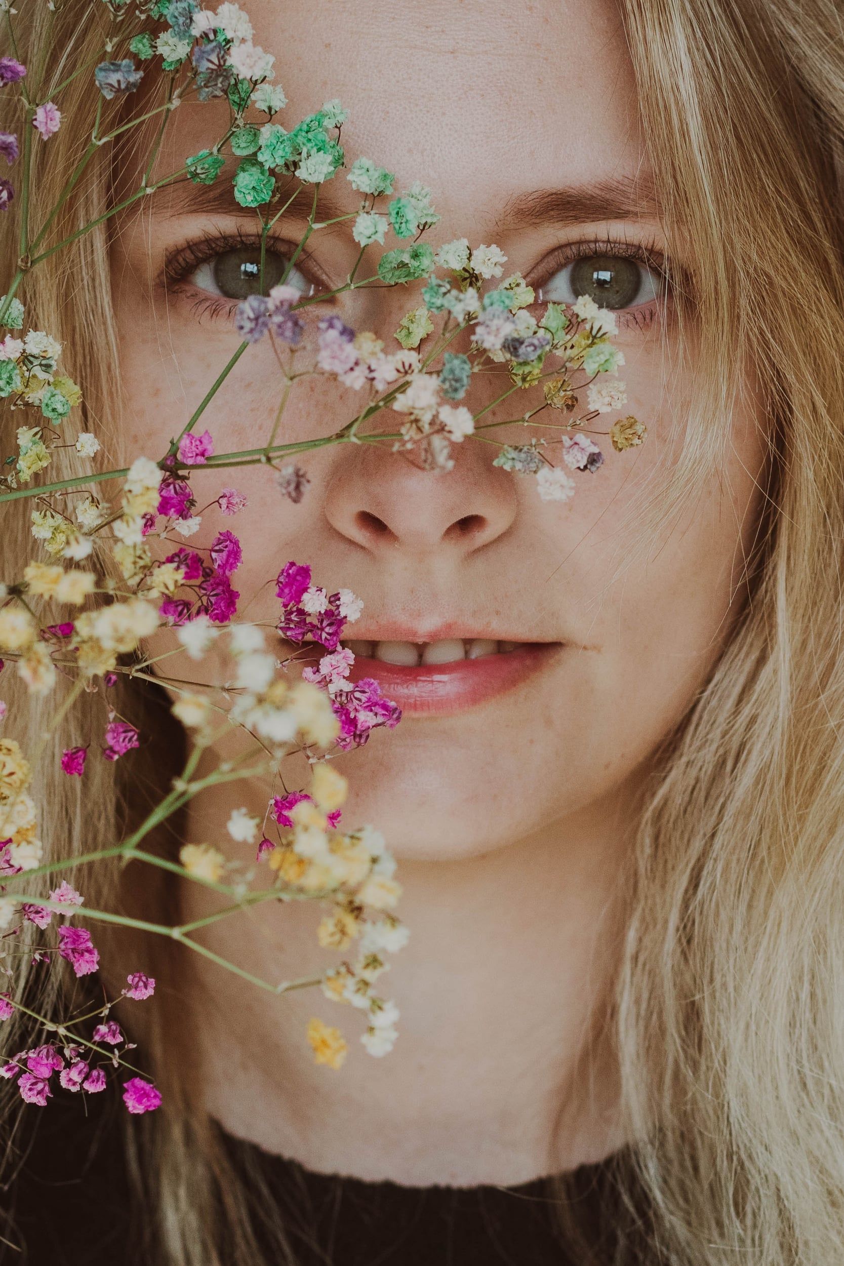 Close portrait of a smiling woman behind a bunch of dried flowers
