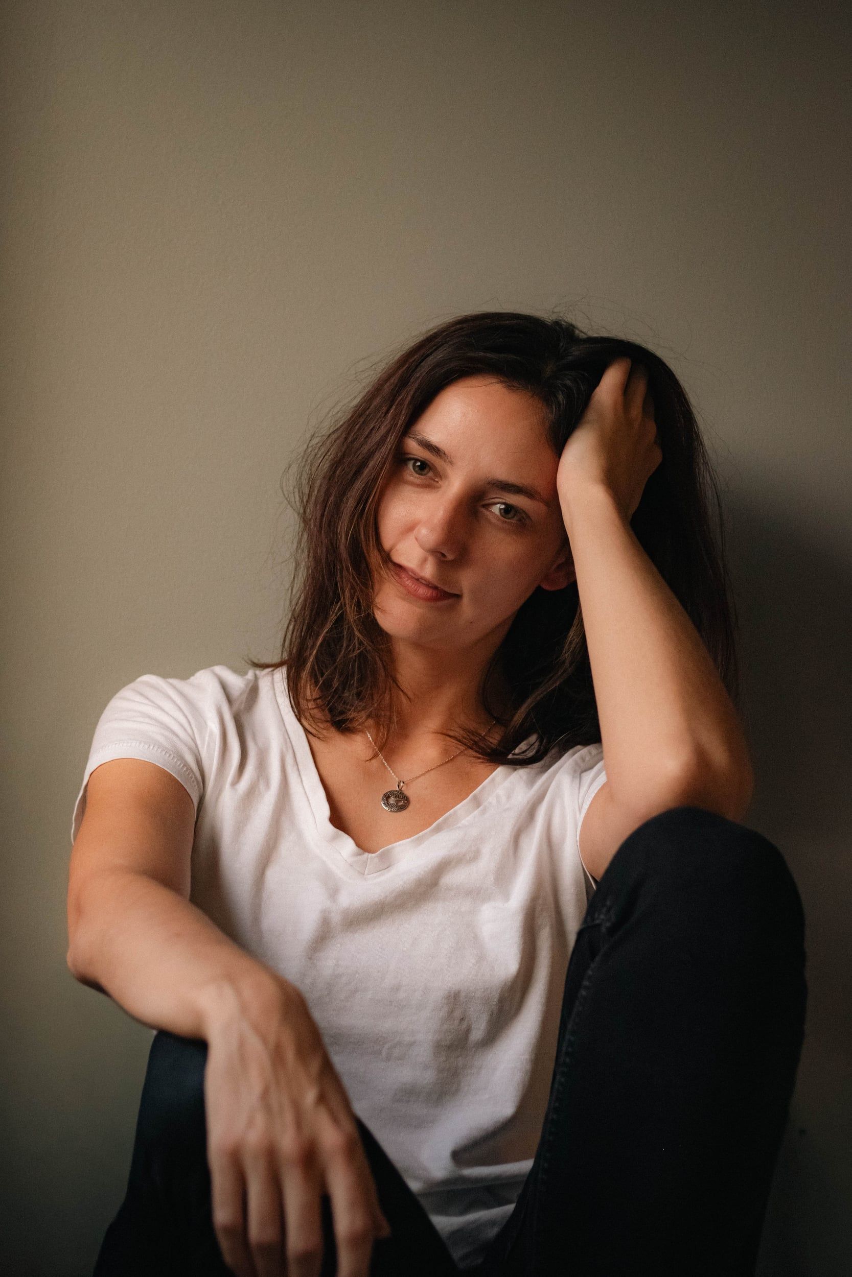 Seated portrait against a grey wall, smiling