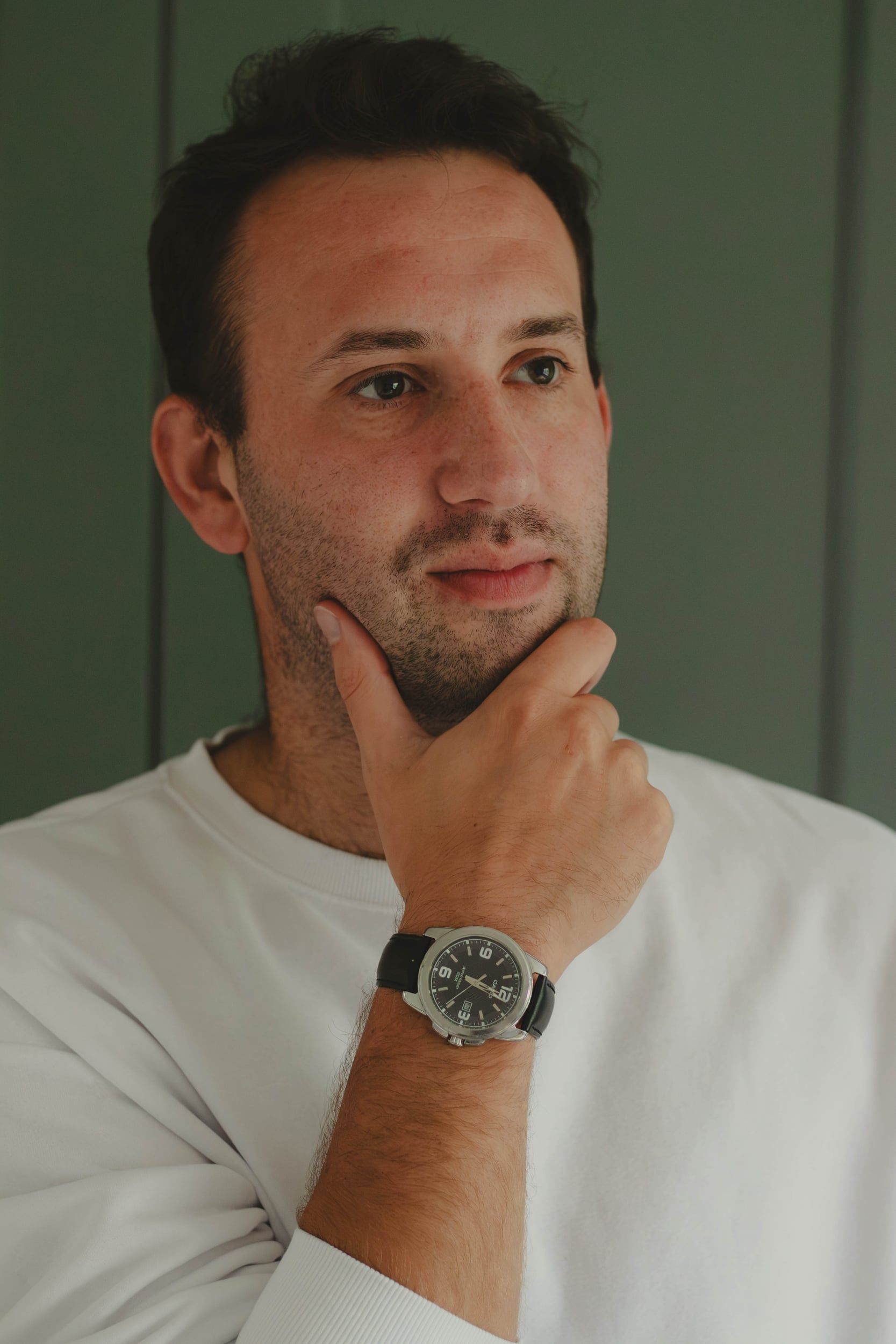 Man in a white jumper, hand on chin